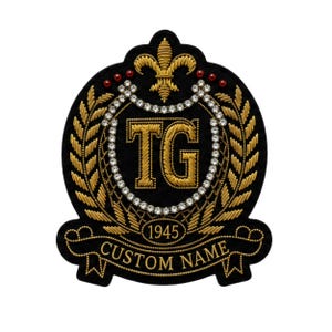 May include: A black embroidered patch featuring a gold fleur-de-lis at the top, the letters TG in gold thread, a circular border of clear rhinestones, gold wheat stalks, the year 1945, and a banner with the text CUSTOM NAME in gold.