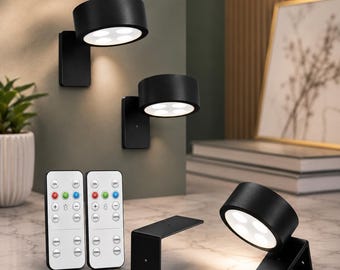 May include: Three matte black cylindrical wall-mounted LED lights with four circular light apertures each. Two lights are mounted vertically, and one is angled on a surface. Two white remote controls with buttons for color and timer settings.
