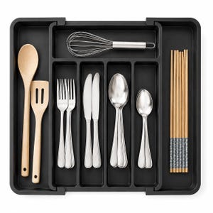 May include: A black expandable cutlery tray organizer featuring multiple compartments. It contains two light wood kitchen utensils, a stainless steel whisk, two forks, two knives, two large spoons, two small spoons, and a set of wooden chopsticks.