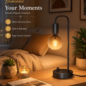 May include: A black metal table lamp with a curved arm and a round base featuring a touch control knob. The lamp holds a large, round, amber-tinted Edison-style light bulb that emits a warm glow. Text on the image reads: Illuminate Your Moments, Simple. Elegant. Essential., Warm & Cozy Glow, Safe & Reliable, Easy Touch Control.