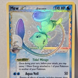 May include: A holographic Mew Delta Species trading card with 110 HP and a water energy symbol. The card features a green and blue Mew illustration, the Tidal Mirage Poke-Body ability, the Aqua Veil attack, and text stating 2026 UNOFFICIAL/CUSTOM CARD.
