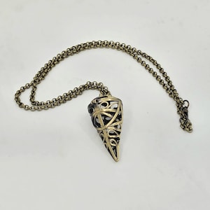 May include: A necklace featuring a cone-shaped pendant with an openwork, cage-like design in a metallic bronze finish. The pendant is suspended from a matching round link chain that features a dark, oxidized texture throughout the metal surface.