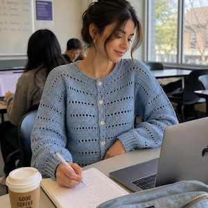 May include: A light blue long-sleeve crochet cardigan featuring a round neckline, ribbed cuffs, and a front button closure with four light-colored buttons. The garment has a repeating horizontal pattern of solid stitches and openwork rectangular gaps.