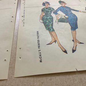 Puede incluir: Dos hojas de patr&oacute;n impreso McCall's vintage con ilustraciones de figuras vistiendo vestidos verdes y azules con accesorios a juego. El papel es de color blanco roto con texto negro y dibujos lineales detallados de la confecci&oacute;n.