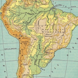 May include: A vintage map of South America, featuring detailed geographical information. The map uses a color-coded system to represent different elevations, with shades of green, yellow, and brown. Major rivers like the Amazon are labeled, along with the Tropic of Capricorn.