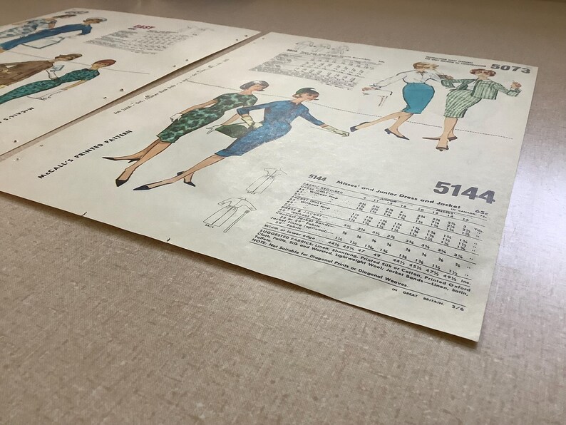 Puede incluir: Dos sobres de patrones de costura vintage de McCall's, n&uacute;meros 5144 y 5073, con ilustraciones de vestidos y chaquetas. El papel de color hueso muestra instrucciones t&eacute;cnicas de costura, requisitos de tela y tablas de tallas en tinta negra.