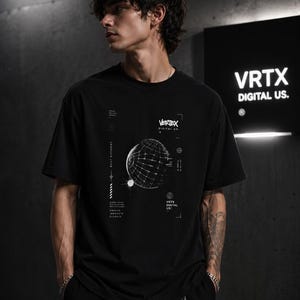 Könnte beinhalten: Ein schwarzes Kurzarm-T-Shirt mit einem weißen Grafikdruck auf der Brust. Das Design zeigt einen Drahtgitter-Globus, den Text "VERTEX DIGITAL US." sowie verschiedene technische Anmerkungen, Koordinaten und kleine geometrische Symbole.