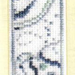 May include: A rectangular, cross-stitched bookmark with a white background and a design in shades of blue and green. The design appears to be an abstract floral or flowing pattern. The bookmark is framed with a blue border.