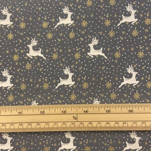 May include: Grey fabric with a white reindeer pattern and gold snowflake accents. The fabric is measured with a ruler in inches.