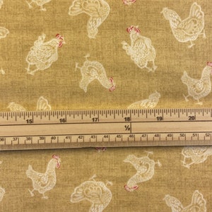 May include: Mustard-coloured fabric featuring a repeating pattern of white chickens with red combs. A wooden ruler with centimetre measurements is laid across the fabric.