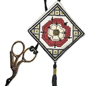 May include: A white and red embroidered needlepoint with a black and gold border and a tassel. The needlepoint features a white flower with a gold centre. A pair of gold scissors with a bird design is included.