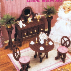 May include: A plastic canvas pattern for a Victorian dollhouse dining room set. The set includes a table, two chairs, a sideboard, and a mirror. The pattern is brown and white.
