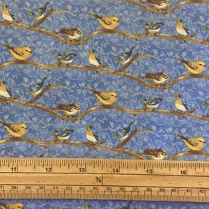 May include: Blue fabric with a repeating pattern of brown branches and yellow and blue birds. A wooden ruler with inch markings is at the bottom of the image.