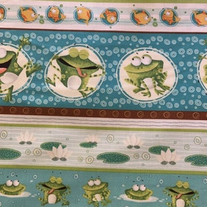 以下が含まれることがあります： カエル、魚、カメ、スイレンが繰り返し描かれたカラフルな生地。生地は青、緑、茶色、白です。