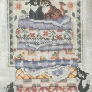 May include: A cross-stitch pattern of three black cats sleeping on a stack of colorful pillows. The cats are in a variety of poses, and the pillows are decorated with different patterns. The pattern is framed by a border of green and red.