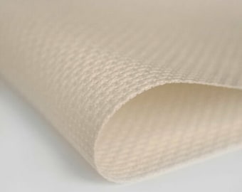 May include: Close-up of a beige fabric with a textured weave. The fabric is folded over on itself, showing the layers.