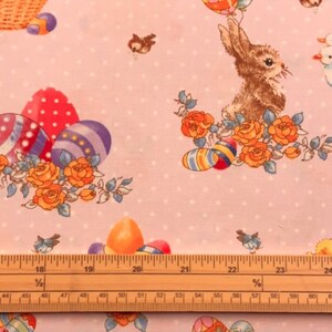 May include: Pink fabric with a repeating pattern of Easter eggs, bunnies, birds, and flowers. The fabric has a white polka dot pattern.