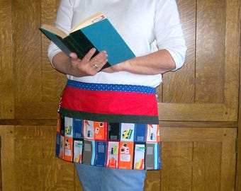 Peut inclure: Un demi-tablier coloré avec un motif de casiers scolaires. Le tablier présente une ceinture à pois bleus, une section centrale rouge et une section inférieure avec un motif répété de casiers de différentes couleurs. Le tablier est porté sur un jean bleu et un t-shirt blanc à manches longues.