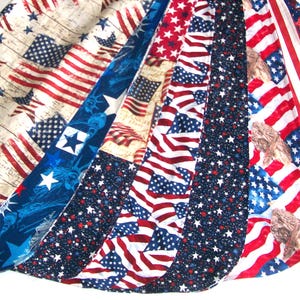 May include: A collection of fabric strips featuring patriotic American flag designs. The fabrics display the stars and stripes in various patterns, including distressed wood grain, blue star fields, and waving flags.