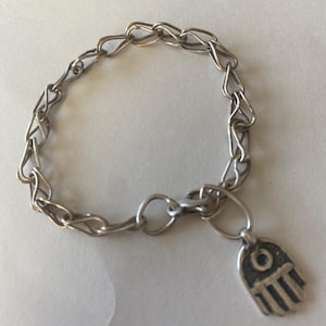 May include: Silver-toned bracelet with a chain link design and a Hamsa hand charm. The bracelet features a lobster clasp closure and is approximately 7 inches in length.