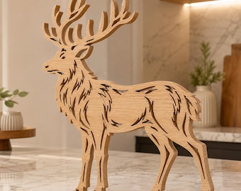 May include: A light brown wooden cutout of a standing deer with large, detailed antlers. The figure features intricate, laser-cut patterns throughout its body, showcasing the natural wood grain texture and a clean, flat profile design.