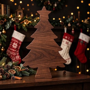 Peut inclure: Une décoration de sapin de Noël en bois brun foncé avec une finition au grain de bois naturel et lisse. L'objet est façonné comme un sapin stylisé avec une étoile pointue au sommet et une base large et plate, posé verticalement comme un objet décoratif.