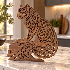 Può includere: Una scultura in legno tagliata al laser raffigurante un leopardo seduto con intricati motivi a macchie e una lunga coda curva. L'oggetto è realizzato in legno marrone scuro con sezioni ritagliate che creano un aspetto stratificato.