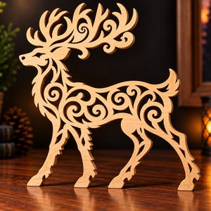 May include: A light-colored wooden cutout of a standing deer featuring intricate, swirling scrollwork patterns throughout its body and large antlers. The deer is depicted in profile, showcasing a detailed, openwork design crafted from smooth wood.
