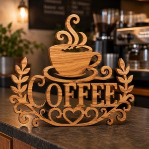以下が含まれることがあります： 大文字でCOFFEEと書かれた明るい茶色の木製サイン。上部には湯気が立ち上るコーヒーカップがデザインされ、両サイドには葉のモチーフ、下部にはハートとスクロール模様が施された装飾的な木製の看板。