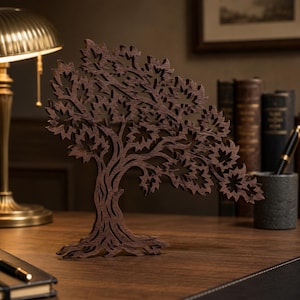 May include: A dark brown wooden sculpture of a tree with intricate, laser-cut leaf patterns and a textured trunk. The decorative piece features a wide, spreading canopy and a sturdy base, standing upright as a standalone ornament on a flat surface.