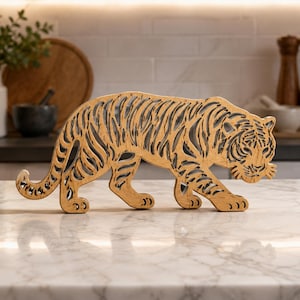 May include: A light brown wooden tiger figurine featuring a detailed laser-cut design with open spaces throughout the body. The tiger is depicted in a walking stance, showcasing a natural wood grain texture and a stylized striped pattern.