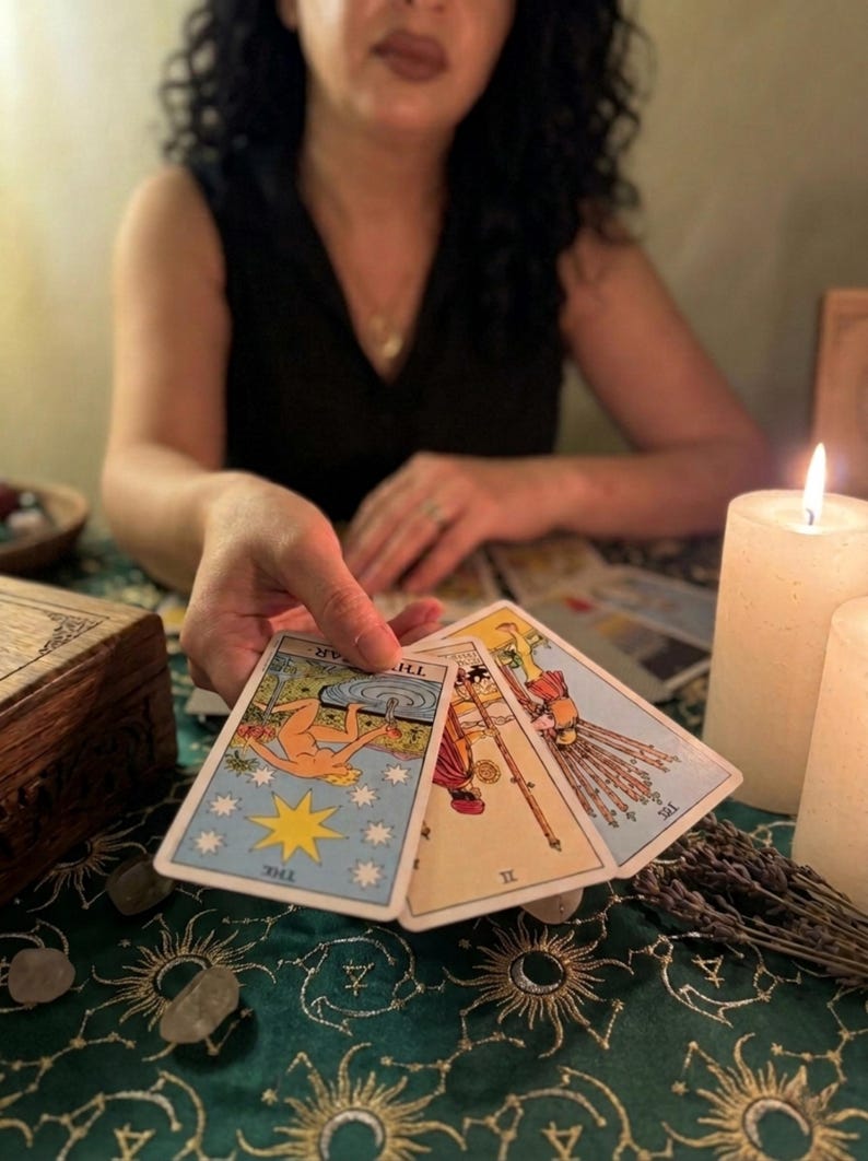 Pode incluir: Tr&ecirc;s cartas de tar&ocirc; seguradas em uma m&atilde;o, incluindo a carta A Estrela com uma figura ajoelhada, a carta Dois de Paus mostrando uma pessoa segurando um globo, e o Dez de Paus retratando uma figura carregando um feixe de dez bast&otilde;es.