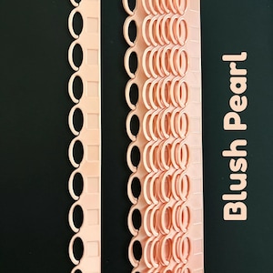 Puede incluir: Dos tiras de encuadernación de plástico color perla rubor con accesorios de anillo circulares. Una tira es de una sola columna, mientras que la otra es una hoja más ancha de varias columnas. El texto "Blush Pearl" está impreso verticalmente.