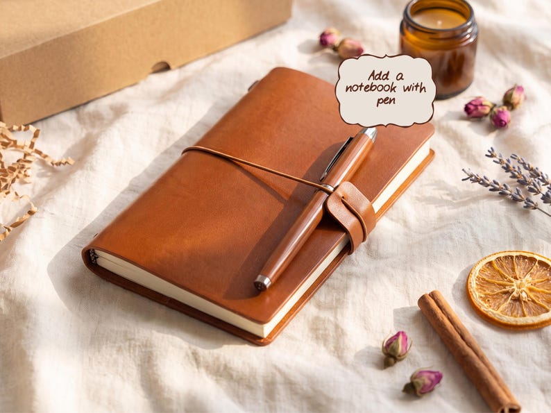 May include: A tan leather notebook with a matching pen secured by a leather strap. A speech bubble graphic above the notebook contains the text Add a notebook with pen. The notebook has a smooth finish and is positioned at an angle.