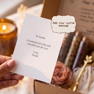 May include: A white rectangular card with black printed text that reads: To Sarah, A moment of calm and warmth just for you. Love, Emily. A brown speech bubble graphic with the text Add your custom message is positioned above the card.