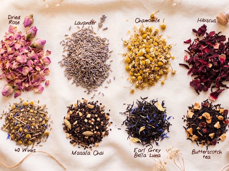 May include: Eight distinct piles of loose-leaf tea and dried botanicals arranged in two rows. The top row features Dried Rose, Lavander, Chamomile, and Hibiscus. The bottom row includes 40 Winks, Masala Chai, Earl Grey Bella Luna, and Butterscotch tea.