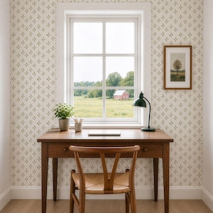 May include: A wooden desk with a woven seat chair, a potted plant, a pencil holder, and a green desk lamp. The wall features off-white wallpaper with a repeating olive green cross pattern. A framed tree print hangs on the wall near a window.