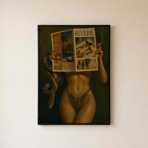 May include: A framed wall art print depicting a figure holding a magazine titled REVERIE in front of their face. The figure wears a snakeskin-patterned bikini bottom, and a large snake is coiled around their right arm. A lit cigarette is held in the left hand.