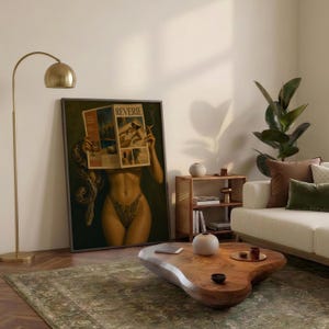 Op de afbeelding: Een ingelijste rechthoekige wandkunstprint met een persoon die een tijdschrift genaamd REVERIE voor het gezicht houdt, met een slang om de arm gewikkeld, tentoongesteld in een kamer met een messing vloerlamp en een houten salontafel.