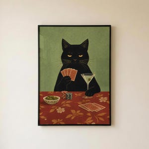 May include: A framed wall art print featuring a black cat sitting at a table covered in a red floral tablecloth. The cat holds a hand of playing cards and a martini glass. A bowl of green olives and poker chips sit on the table surface.