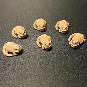 以下が含まれることがあります： グループで配置された5つの小さな日焼け色のトカゲの置物。各トカゲは、質感のあるでこぼこした背中、明るい色の腹部、湾曲した尾、小さな黒い目を特徴としています。フィギュアは、はっきりとした頭と体の形に彫刻されています。