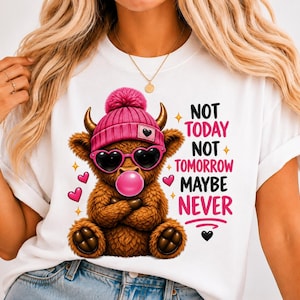May include: A white t-shirt featuring a graphic of a brown highland cow wearing a pink knit beanie and heart-shaped sunglasses while blowing a pink bubble. The text reads NOT TODAY NOT TOMORROW MAYBE NEVER, accompanied by small pink hearts and yellow stars.