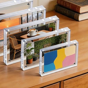 May include: A set of five rectangular clear acrylic photo frames of varying sizes, each featuring four silver-toned metal corner fasteners. The frames are arranged in a row, displaying various landscape and abstract color block images.
