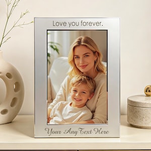 May include: A rectangular silver-toned metal picture frame with a smooth finish. The top border is engraved with the text "Love you forever." and the bottom border features the engraved text "Your Any Text Here." It holds a portrait photo.
