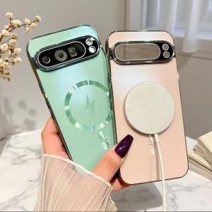 May include: Two smartphone cases with metallic edges and camera cutouts. One case is mint green with a circular magnetic charging ring design, and the other is pale pink with a white circular magnetic charger attached to the back surface.