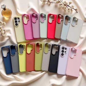 Könnte beinhalten: Eine Sammlung einfarbiger Smartphone-Hüllen, die in zwei Reihen angeordnet sind. Die Hüllen verfügen über einen Ausschnitt für ein Multikamera-System und sind in verschiedenen Farben wie Pink, Gelb, Grün, Rot, Braun, Blau, Grau, Schwarz und Weiß erhältlich.