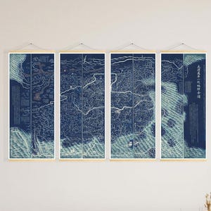 Peut inclure: Quatre panneaux d'art mural représentant une carte détaillée en bleu et blanc. L'œuvre est affichée au-dessus d'un canapé sectionnel beige. La pièce est décorée d'éléments naturels, dont une table basse en osier et des décorations murales. Les mesures sont en cm.