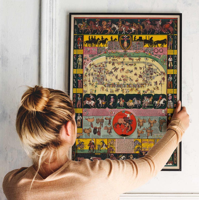 Puede incluir: Un p&oacute;ster vintage enmarcado con una colorida ilustraci&oacute;n de una escena de rodeo. La obra de arte presenta vaqueros a caballo, eventos de rodeo y varias ilustraciones de equipos de rodeo. El p&oacute;ster tiene un marco negro y lo sostiene una persona.