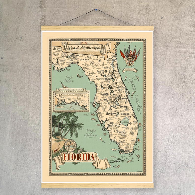 Pu&ograve; includere: Una mappa illustrata della Florida in stile vintage stampata su uno sfondo beige chiaro con un mare verde pallido. La mappa presenta disegni dettagliati di monumenti, fauna selvatica e una rosa dei venti, incorniciata da un supporto in legno e appesa a un filo nero.