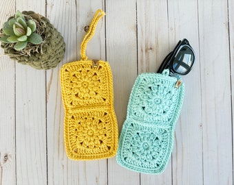 Pode incluir: Dois estojos para óculos de sol de crochê, um amarelo e outro azul claro, com um design floral. Os estojos são feitos de dois quadrados que se dobram juntos.